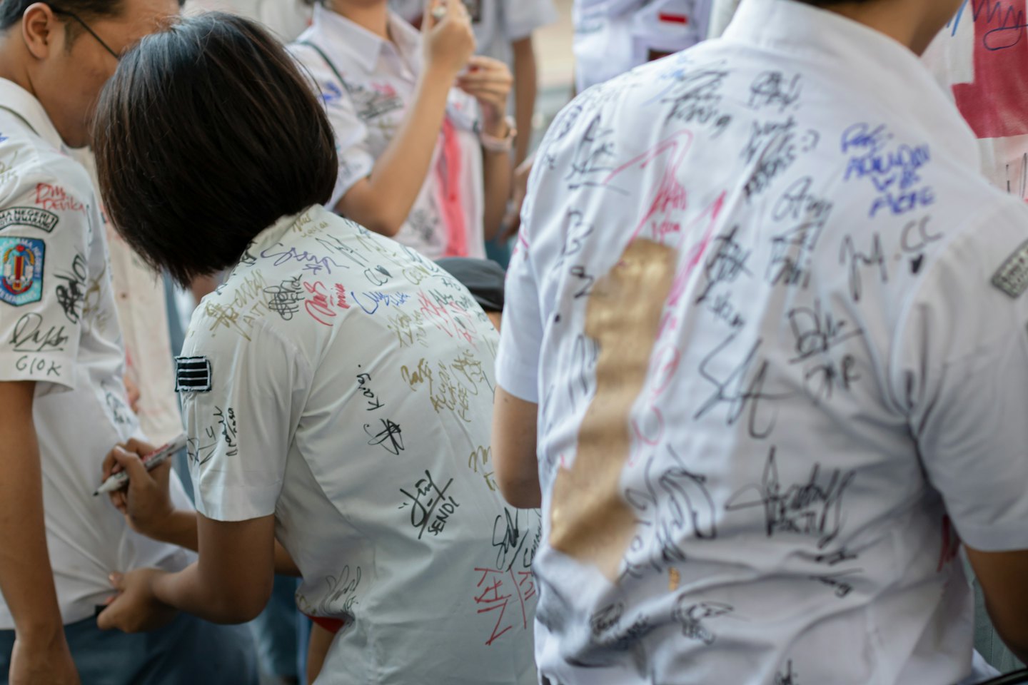 Students use markers to sign signatures on each others shirts.